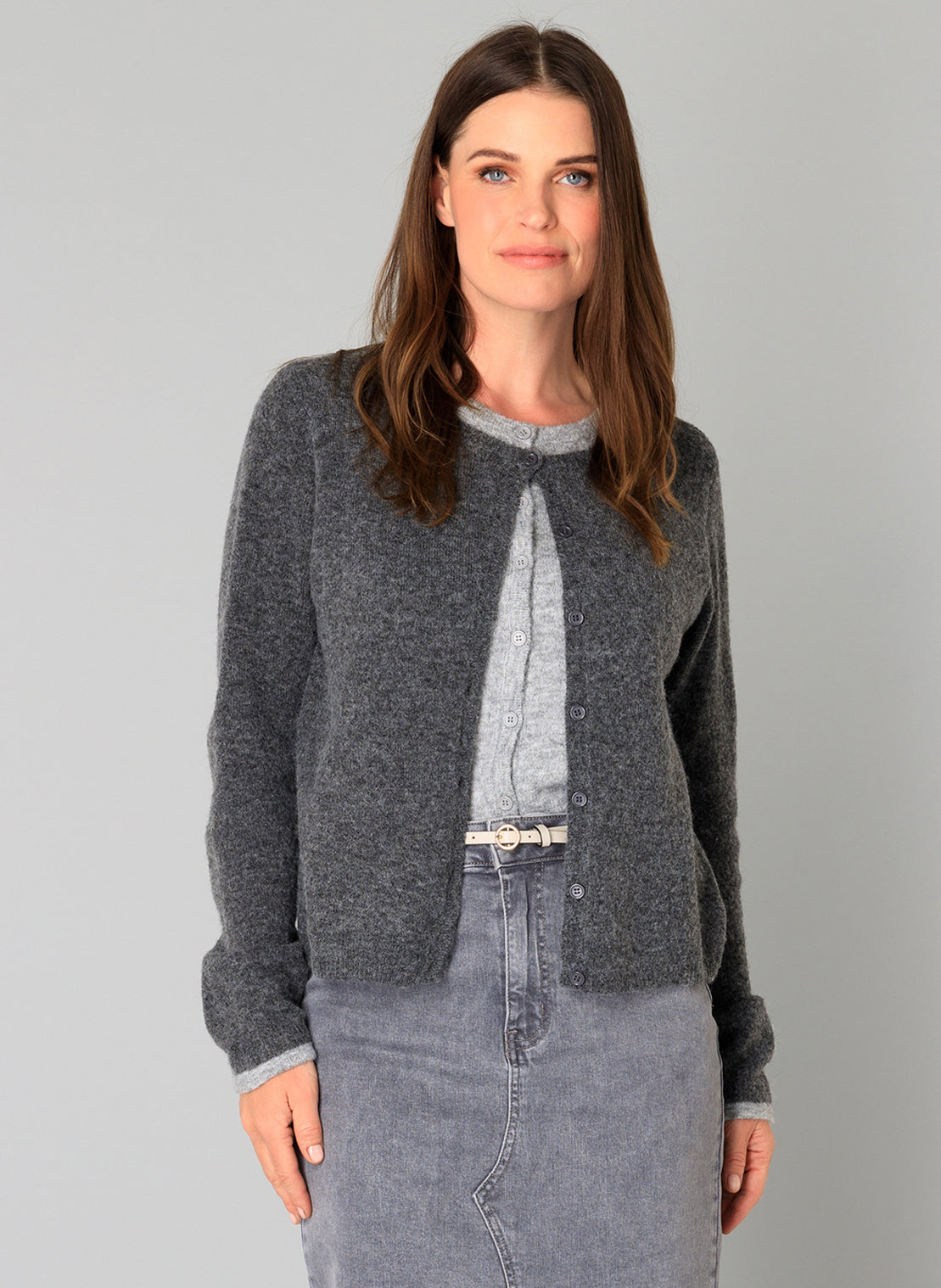 Woman wearing a faux layer grey cardigan with denim skirt