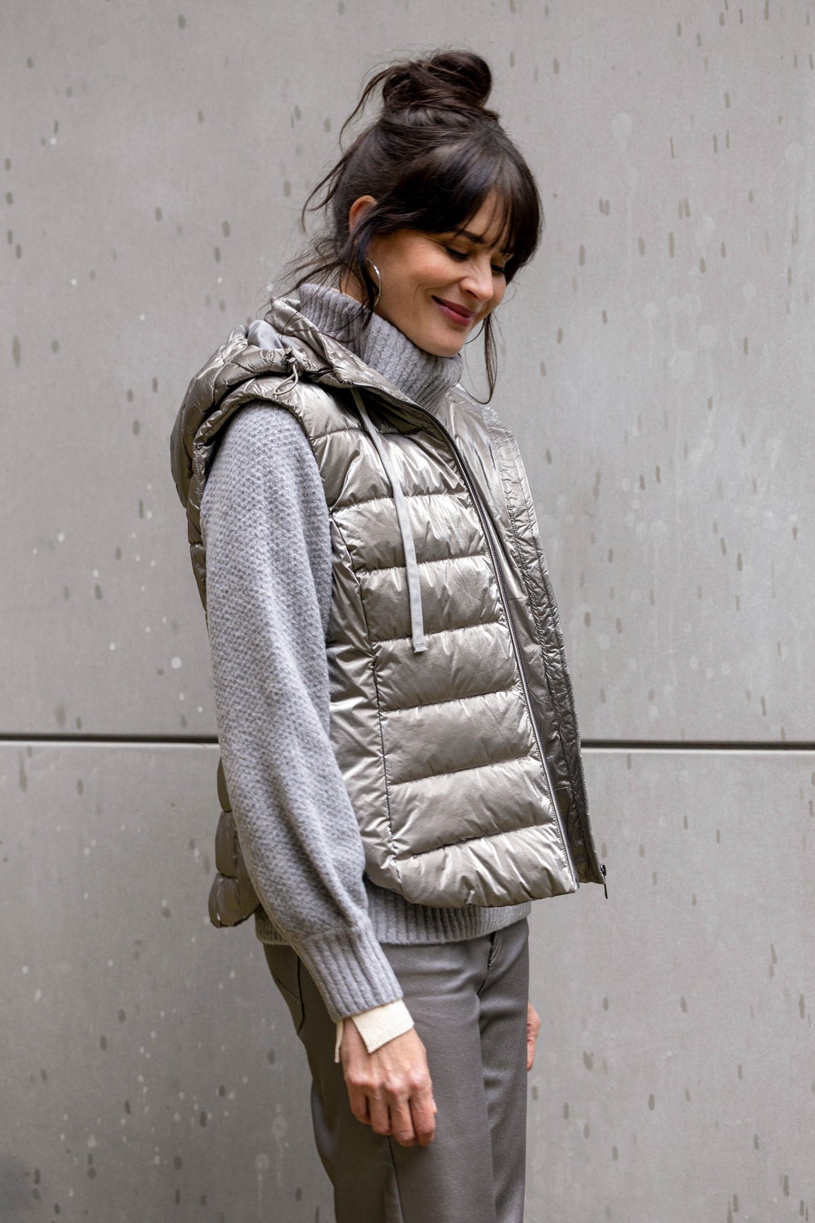 Woman wearing a silver grey puffer vest over a grey sweater