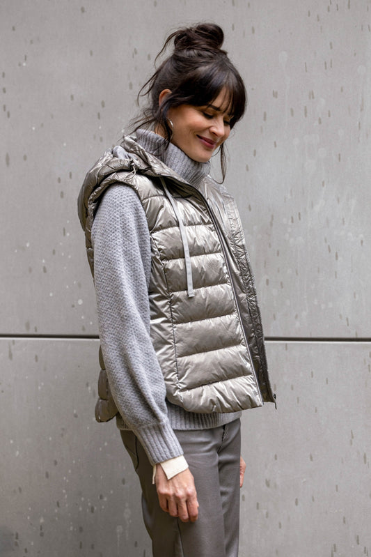 Woman wearing a silver grey puffer vest over a grey sweater