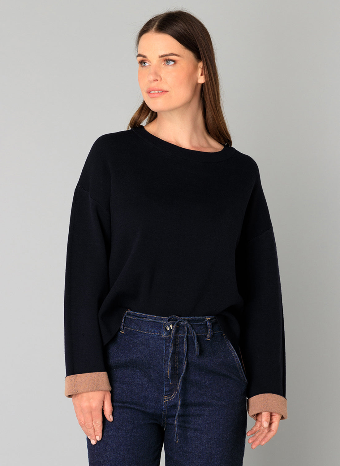 Woman wearing a navy sweater with sand contrast cuff trim