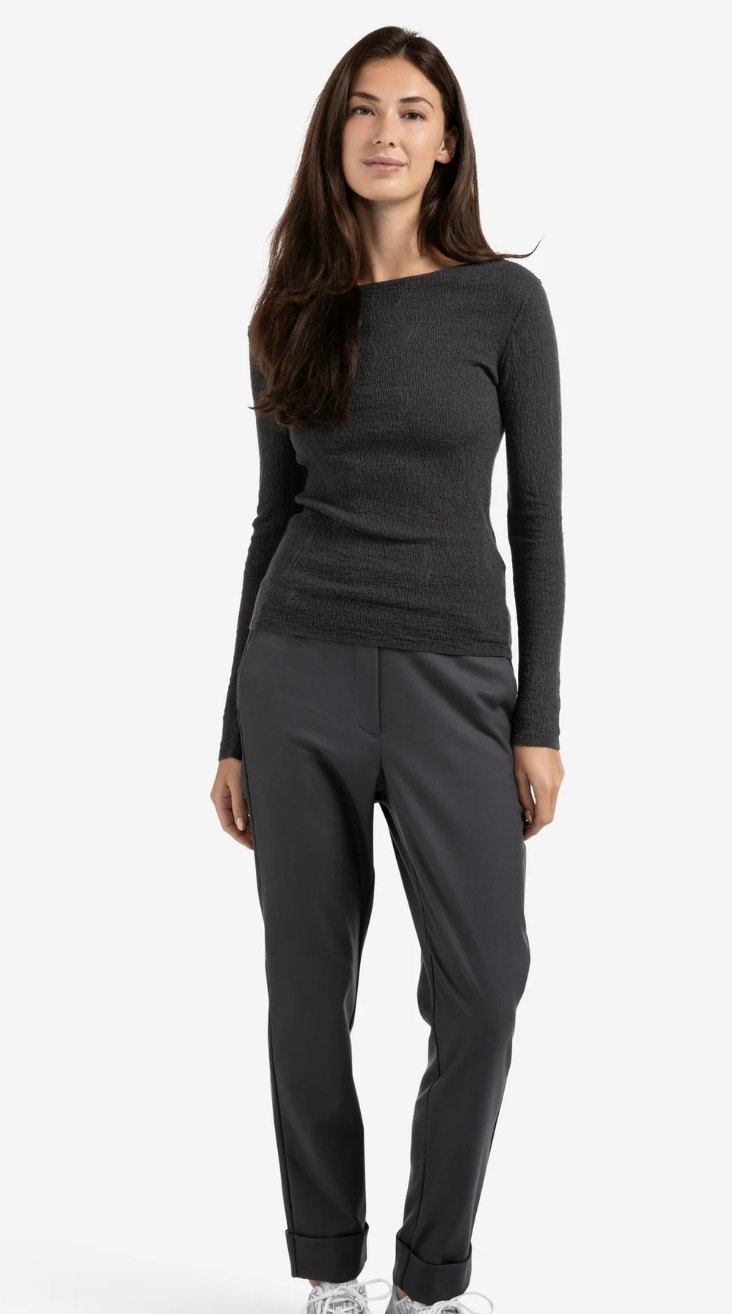 Woman wearing a gray long-sleeve top and hem turn up dark grey pants on a white background