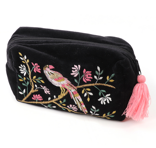 Black pouch with bird and floral embroidery and a pink tassel on a white background