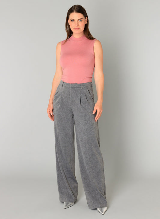Woman wearing a pink sleeveless top and gray wide-leg pants on a gray background