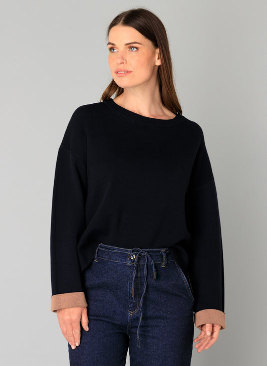 Woman wearing a navy sweater with sand contrast cuff trim 