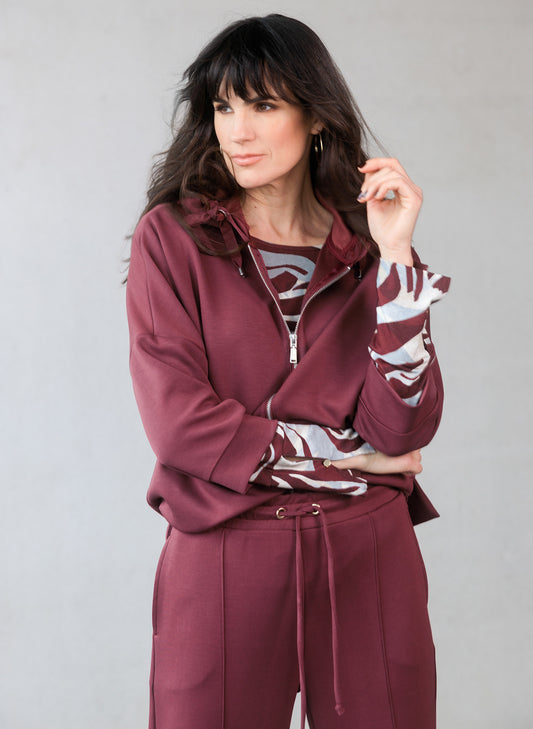 Woman wearing a wine hoodie with a patterned shirt underneath 