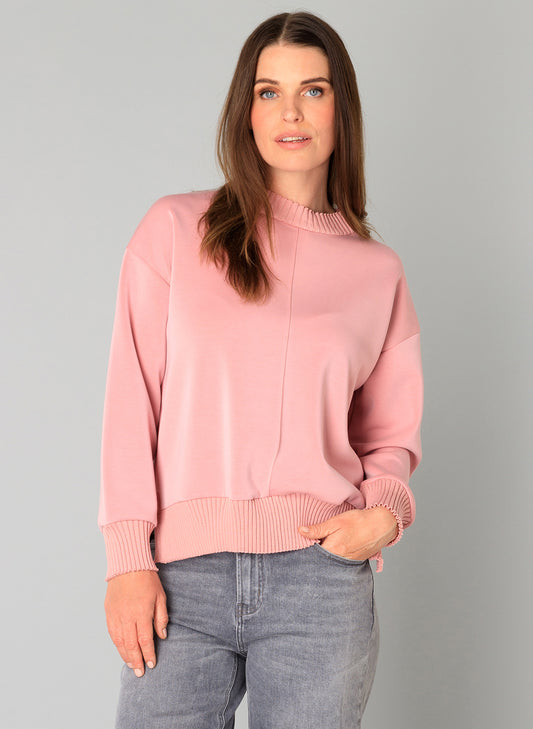 Woman wearing a pink soft modal top and grey jeans 