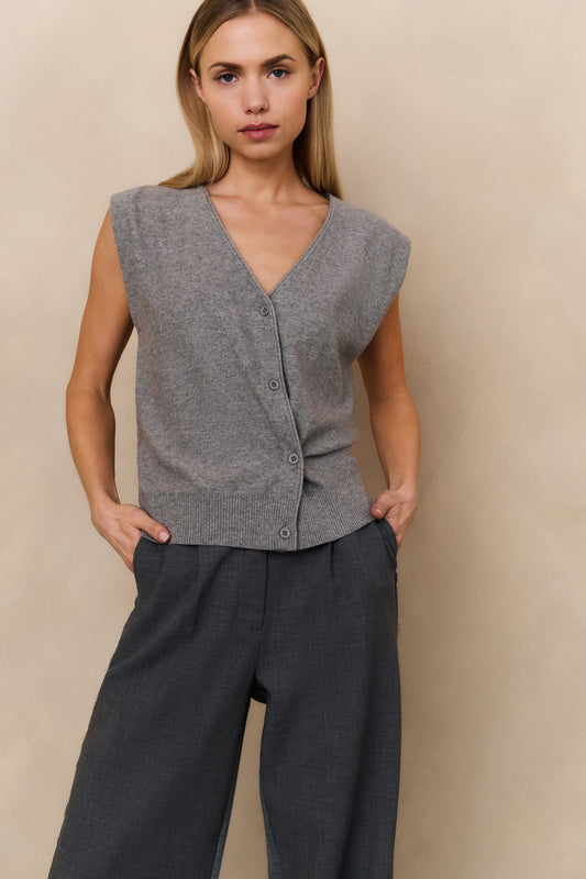 Woman wearing a grey sleeveless knit top and dark pants 