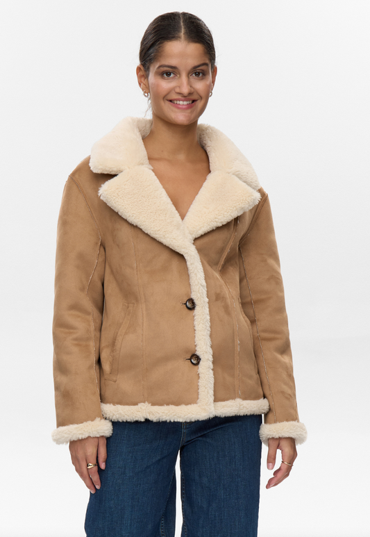 Woman wearing a tan shearling jacket with white fur trim on a white background