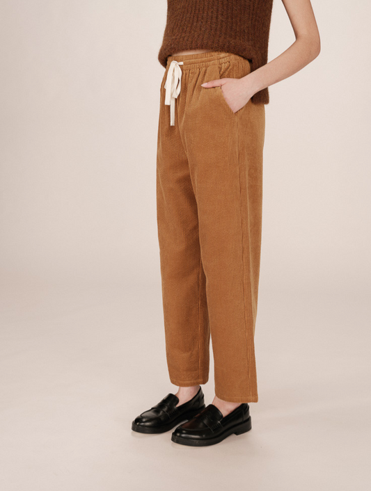 Person wearing mustard corduroy pants with cream tie waist