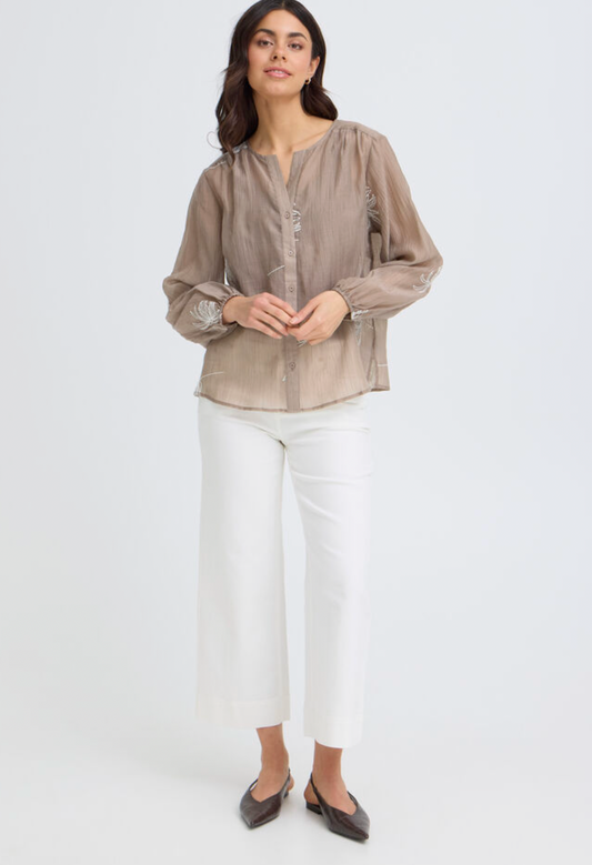 Woman wearing a beige blouse and white pants on a white background